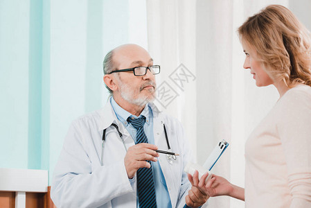 高级医生和在诊所内携带药物的女病图片