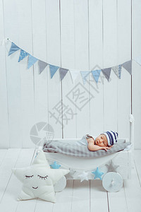 穿着帽子的可爱婴儿宝睡在木制婴儿床里图片