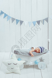 穿着帽子睡在与星装饰的木头婴儿床上的图片