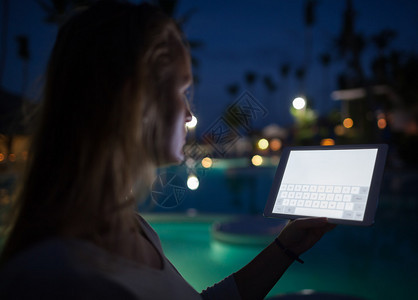 晚上在热带度假胜地使用平板电脑的妇女屏图片