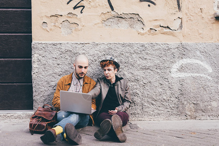 两个年轻的白人男女坐在城市户外的地板上图片