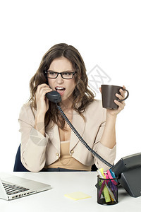 一位愤怒的女商人在她的办公桌上接听电图片