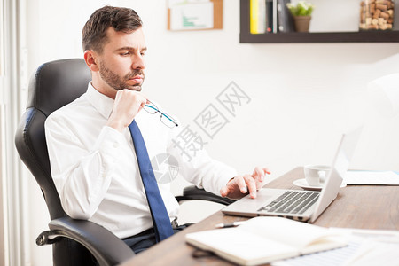 长着胡子的帅气年轻男子在笔记本电脑上工作图片