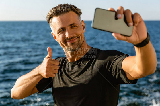 快乐的成年男人用智能手机拍自在图片