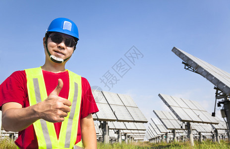 快乐的工人拿着拇指站立在太阳能电池图片