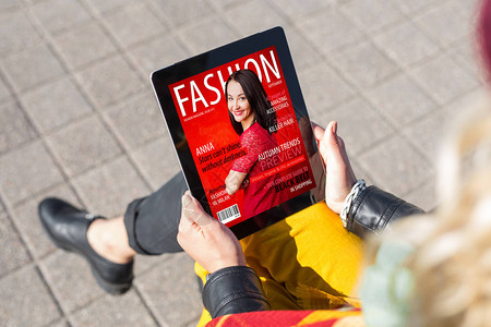 电子杂志在平板电脑上阅读时尚杂志的女背景