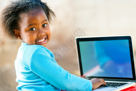 在笔记本电脑上工作的非洲可爱学生显示空白的屏图片