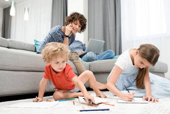 两个孩子在客厅的地毯上画妈在沙图片