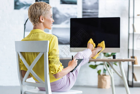 在家办公室用电脑在桌边的图形平板上工作的女图片
