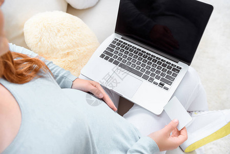 孕妇在家中使用笔记本电脑和信用卡在图片