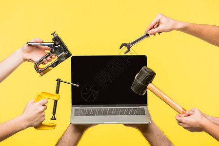 手握工具和膝上型电脑用黄色隔绝的图片