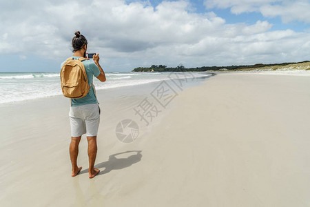 在新西兰拉瓦海滩使用智能手机拍摄海岸线照图片