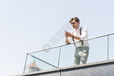 在阳台上使用智能手机的英俊青年图片