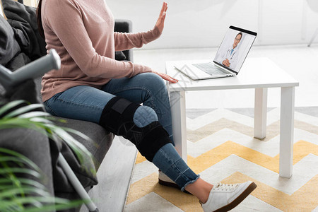 家庭笔记本电脑上与医生进行在线咨询的断腿妇女被图片
