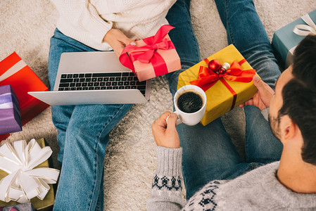 两人在使用笔记本电脑和喝咖啡的同时互相赠送圣诞礼物图片