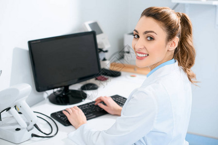 美丽的眼科医生在诊所用电脑工作笑着微图片