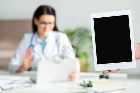 在诊所办公室里手持带空白屏幕的数字平板电脑的人剪影图片