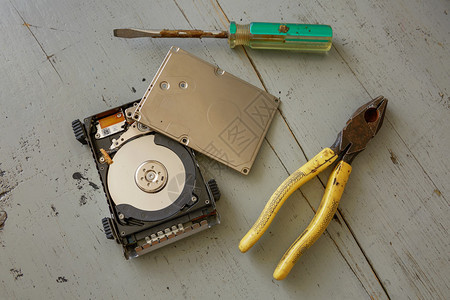 木桌上的损坏和损坏的硬盘驱动器磁盘和工具图片