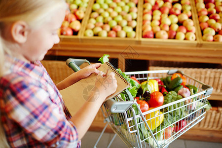 现代儿童在访问超市绿化部门时写下购物清单图片