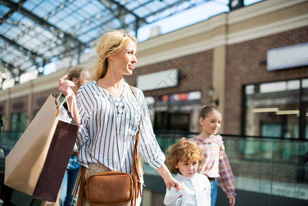 与孩子一起在购物商场步行的手袋中和母图片