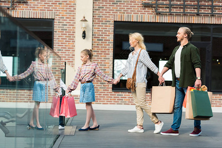 幸福的年轻家庭持有纸袋和在购物中心一图片