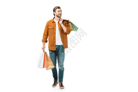 快乐的男子行走着色彩多的购物袋在白图片