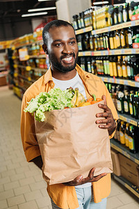 微笑的非洲裔美国男购物者拿着纸袋在超市里图片