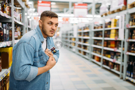 男子在超市的衬衫下藏着一瓶酒图片