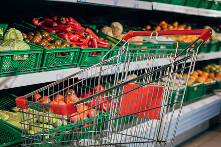 超市空购物车和新鲜蔬菜的选择焦点有背景图片