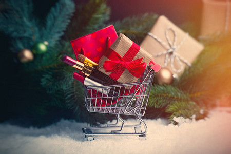 雪背景下的圣诞礼物和带化妆品的购物车图片