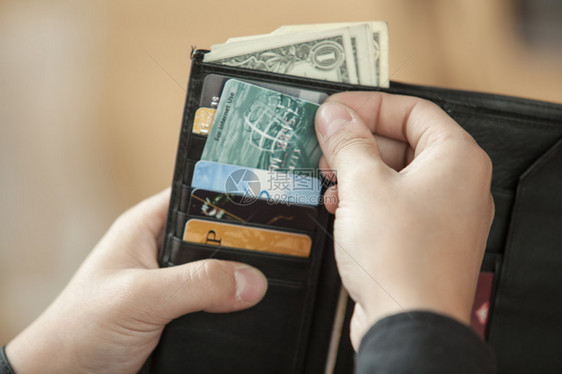 男人的手从黑色钱包里掏出一张信用卡图片