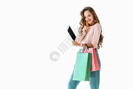 带着购物袋用平板电脑和信用卡在网上购物的年轻微笑图片