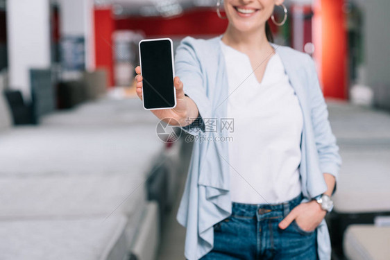在有床垫的家具店铺用空白屏幕显示智能手机的微笑妇女被拍图片