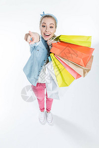 快乐的年轻女士拿着购物袋指背景图片