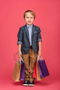 可爱的小可爱男孩手拿着购物袋在粉红图片
