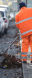 一个穿橙色衣服的街头清洁工收集街图片