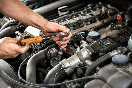 机械师在汽车间维修或维修期间使用汽车发动机上的扳手和套图片