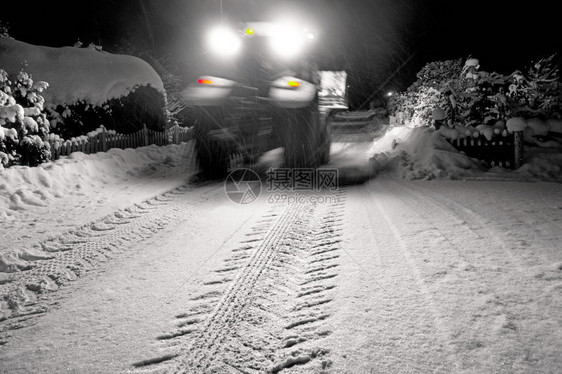 深夜在郊区公路上清除雪的模糊图片