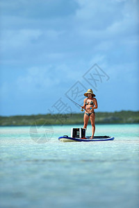 穿比基尼比基尼的漂亮女子从桨板到风景优美热图片
