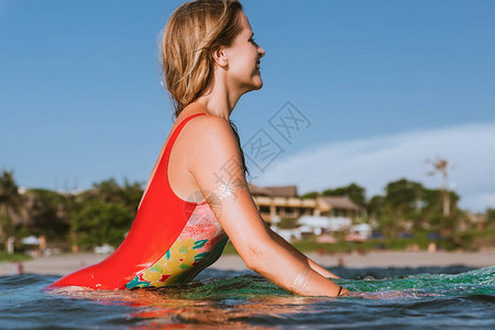 身穿泳衣的年轻漂亮女人在海洋冲浪板上休息的侧视图图片