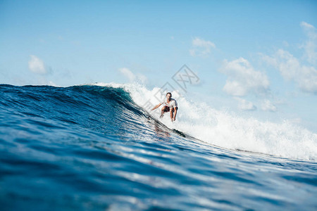 英俊的员在阳光明媚的日子在海浪上冲浪图片