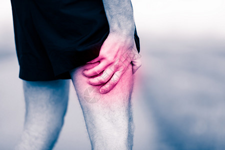 男人拿着酸痛的腿部肌肉扭伤或抽筋疼痛图片