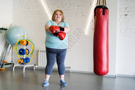 穿着拳击手套在健身训练时面对照相机的拳击手套的笑着胖图片