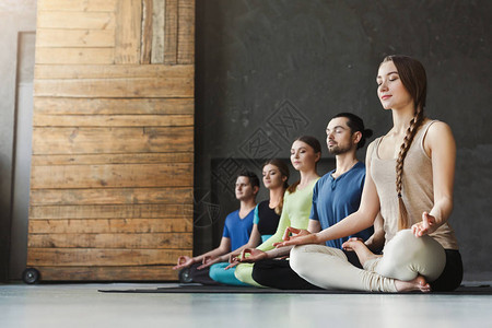瑜伽课冥想练习的男女青年男女Lotus代表了放松健身俱乐部作物和复制空间的图片