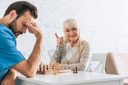 笑着的老女人用手指尖看着在下棋比赛后心图片