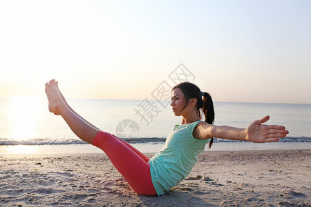 年轻漂亮的女人在沙滩上做瑜伽图片