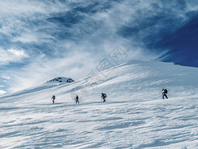 在美丽的雪盖高山上攀爬的远足者的另一侧图片