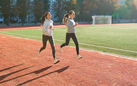 两名在运动场赛道上跑步的健身女子图片
