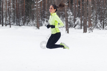 运动女慢跑女运动员在冬季公园森林图片