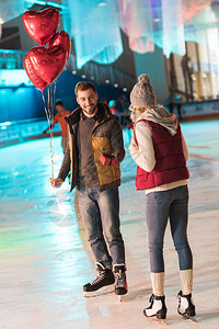 快乐的年轻男子与气球展示礼物盒给女朋友图片